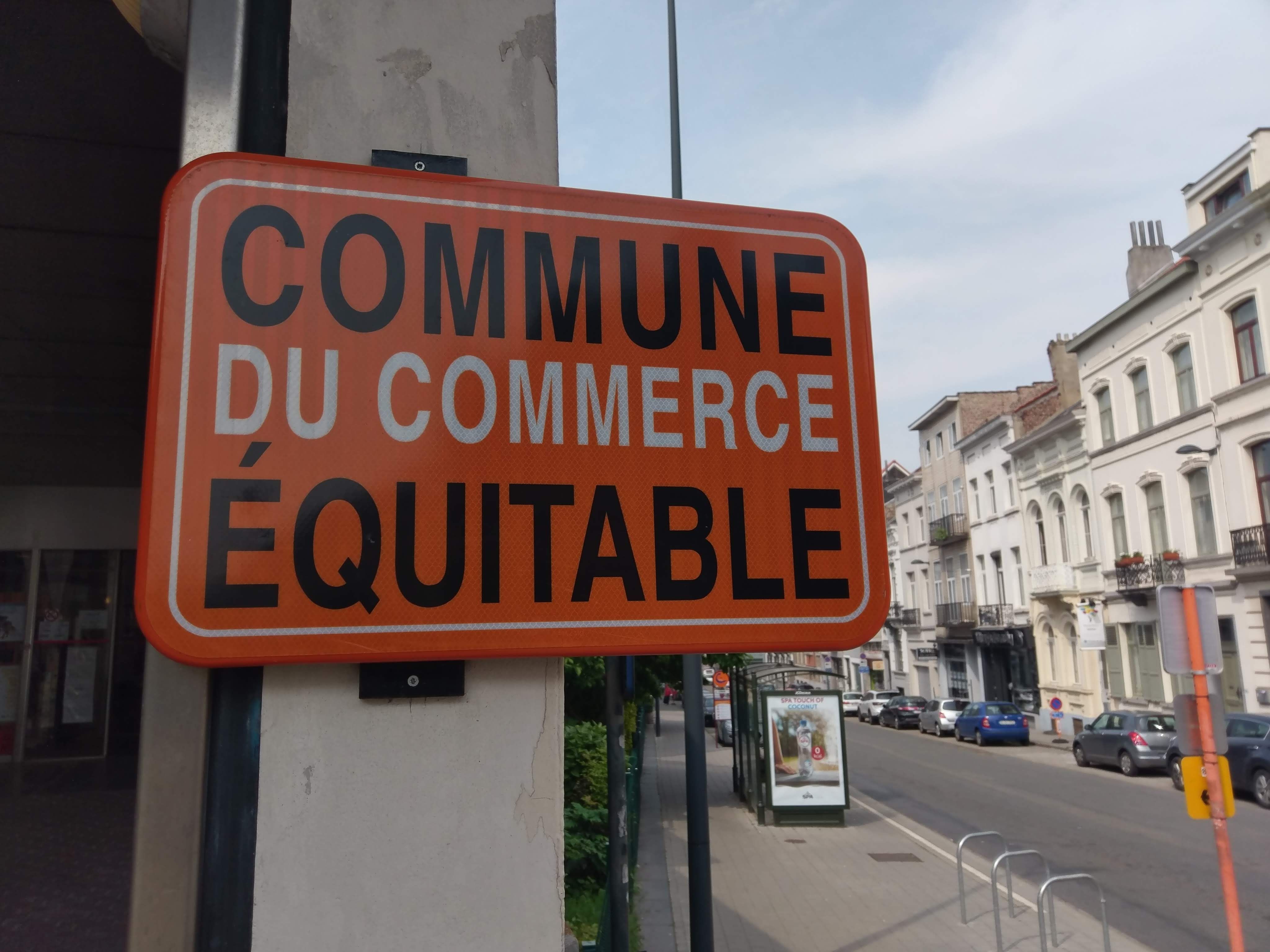 un panneau orange avec l'inscription "COMMUNE DU COMMERCE ÉQUITABLE"